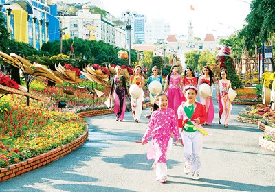 Young women dressed in traditional outfits walk through Nguyen Hue Flower Street (Photo:SGGP)